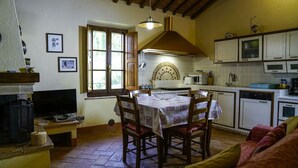 Une cuisine chaleureuse avec une table à manger, des chaises en bois, un four encastré et une fenêtre donnant sur un beau paysage.