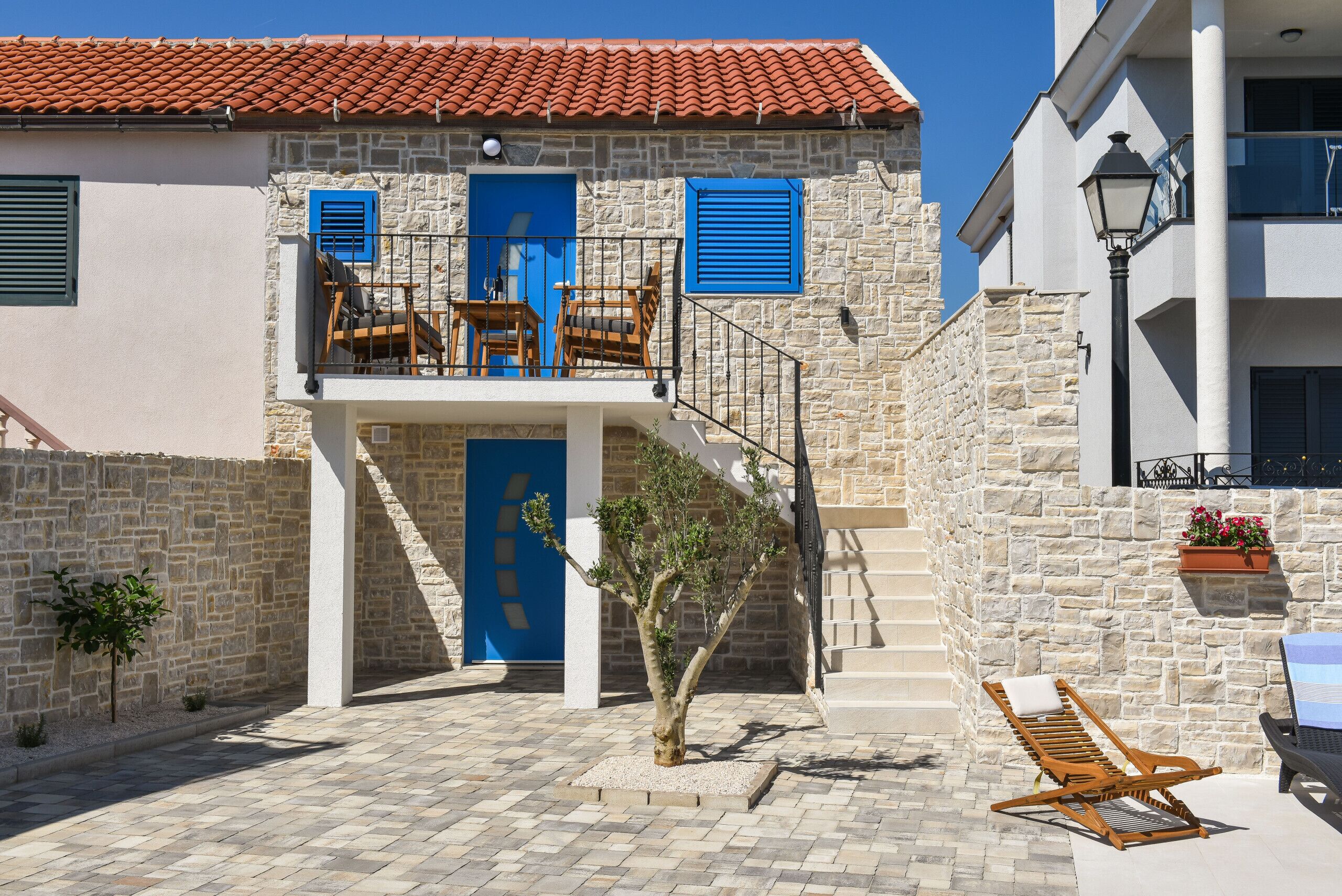 A stone building with a balcony, a staircase, and outdoor seating.