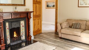 A living room with a fireplace, wooden door, and a beige sofa. - Woodlawn (Kilmore)