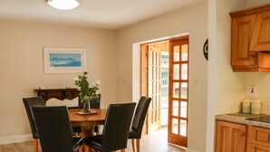 A dining area with a wooden table and chairs, a vase with flowers, and a painting on the wall. - Woodlawn (Kilmore)
