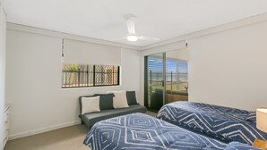 Une chambre avec deux lits, un ventilateur de plafond, une fenêtre avec vue et une petite table.