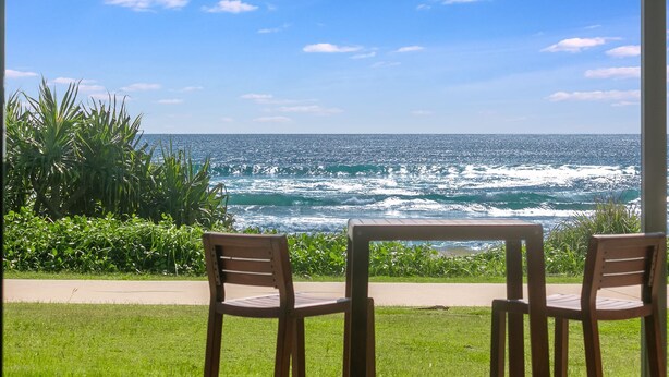 Une vue sur l’océan depuis une terrasse avec deux chaises en bois, toutes deux tournées vers la mer.
