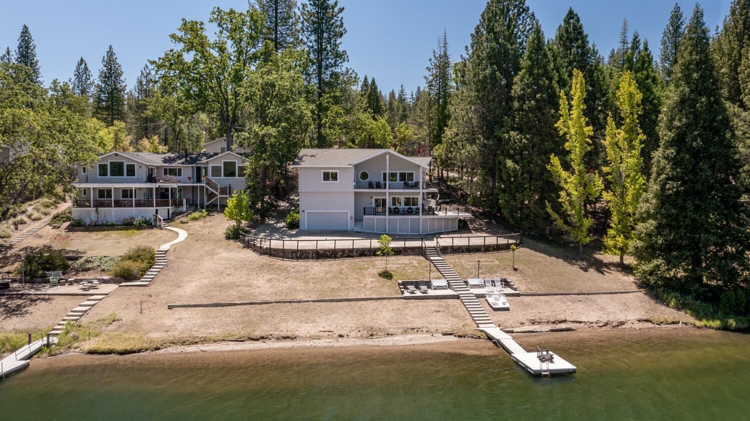 A lakeside property with multiple buildings, a dock, and a well-maintained lawn.