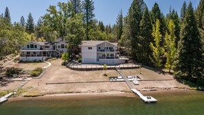 Une propriété située au bord d’un lac, comprenant plusieurs bâtiments, un quai et une pelouse bien entretenue.