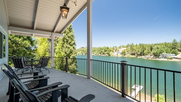 Une terrasse couverte avec des sièges extérieurs, donnant sur un lac et offrant une vue sur le paysage environnant.