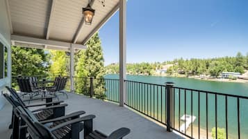 Um deck coberto com área de estar ao ar livre, com vista para um lago e paisagem circundante.