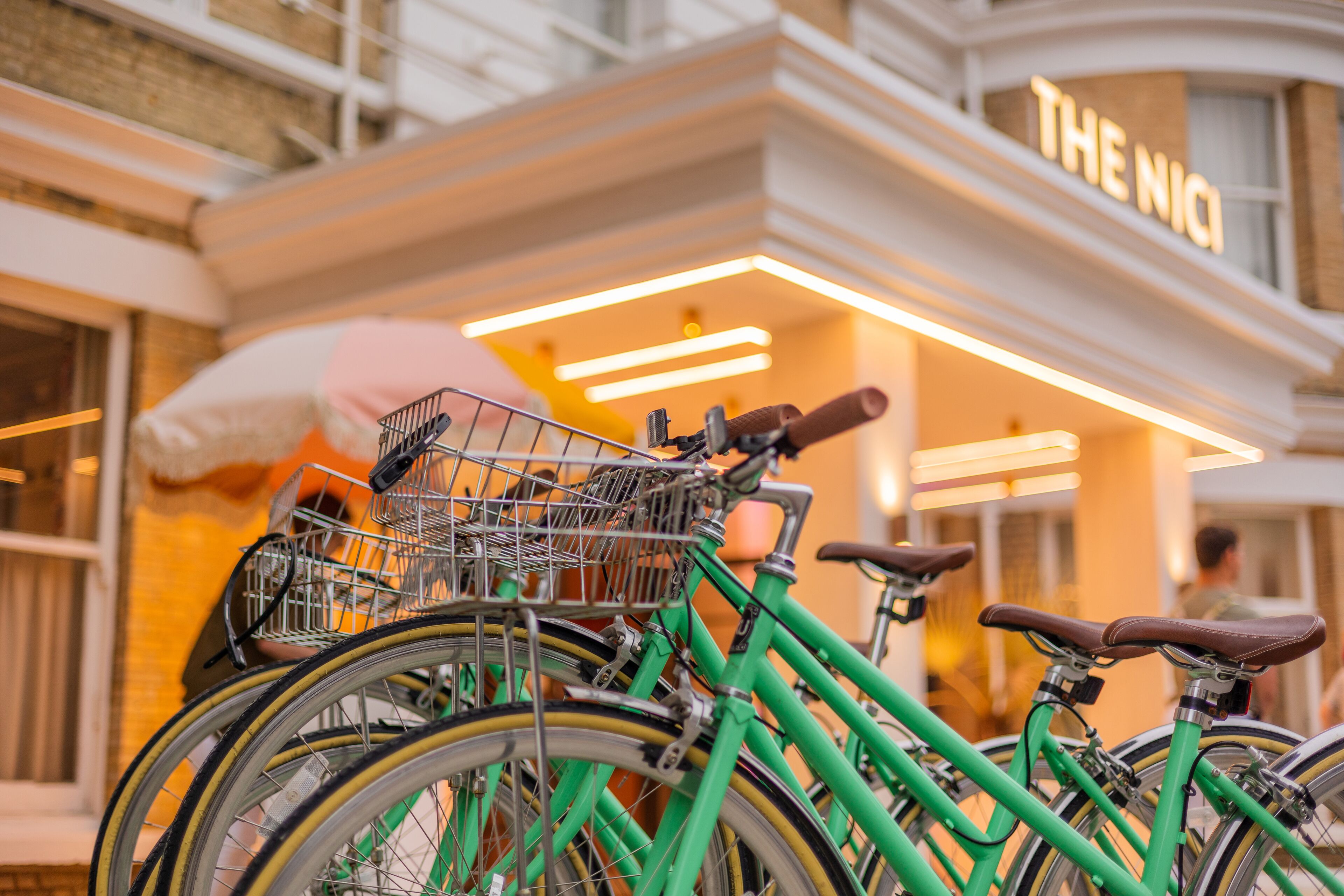 A row of bicycles parked outside a building with a sign that reads "THE NICO".