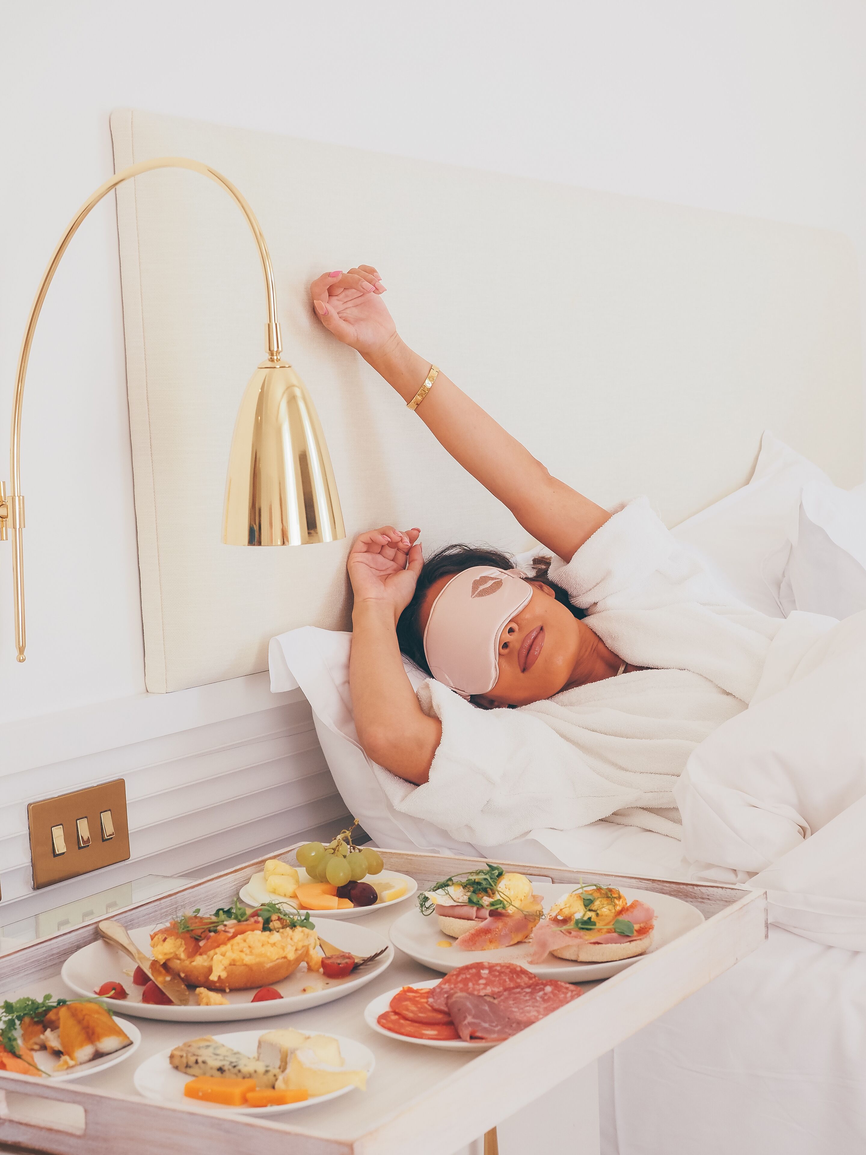 A person lying in bed with a breakfast tray in front of them.
