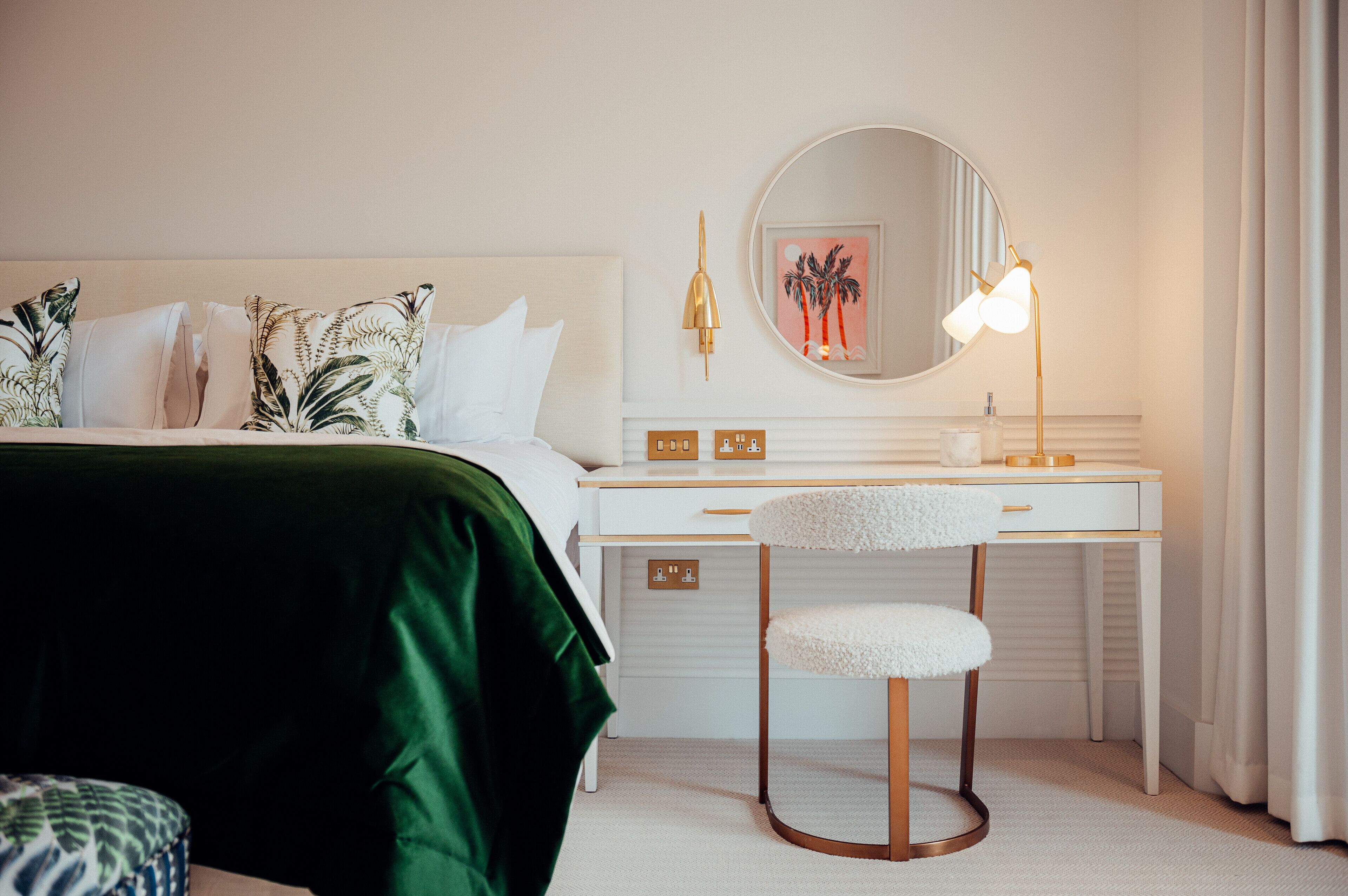 Un dormitorio con una cama, un escritorio, una silla, un espejo y una lámpara.