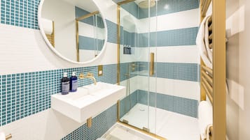 A bathroom with a white sink, a round mirror, and a glass-enclosed shower.