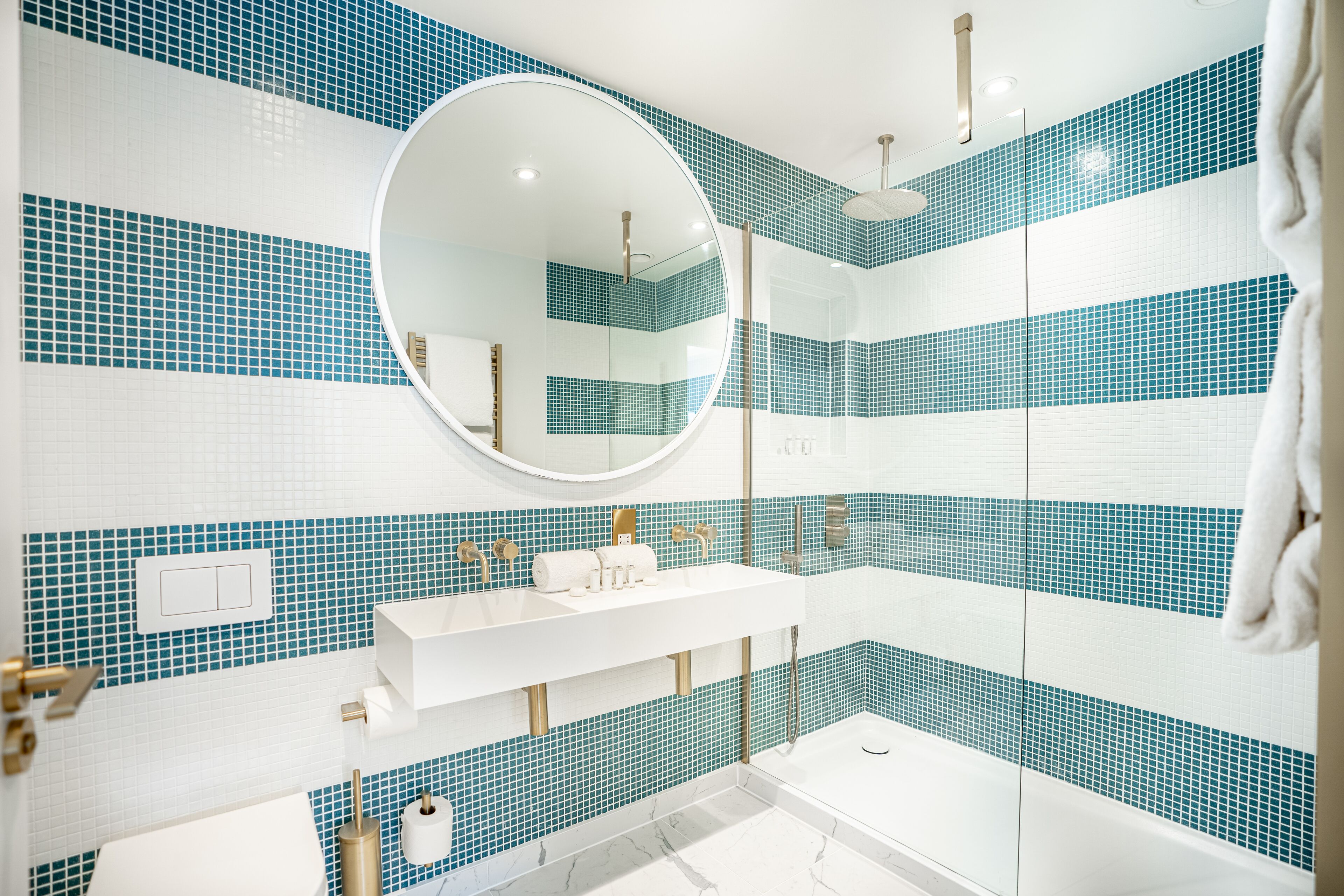 A modern bathroom with a white sink, a mirror, and a shower area.