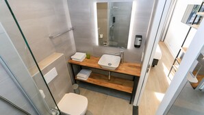 Une salle de bain moderne avec une douche à parois de verre, un meuble-lavabo en bois et des toilettes.