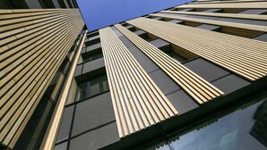 Un bâtiment moderne doté d’une façade originale, caractérisée par des lambris en bois verticaux et de grandes fenêtres.