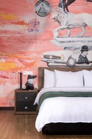 Un dormitorio con cama, mesita de noche y un mural en la pared.