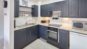 Una cocina moderna con armarios oscuros, un lavamanos de acero inoxidable, un microondas y un horno empotrado.