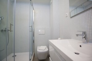 Bathroom features a glass-enclosed shower, toilet, sink, and mirror.