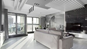 Een moderne woonkamer met een grote bank, een flatscreen televisie en een stadsgezicht muurschildering.