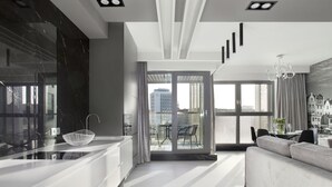 Een moderne keuken met een groot eiland, een eethoek met een tafel en stoelen, en een stadszicht door grote ramen.