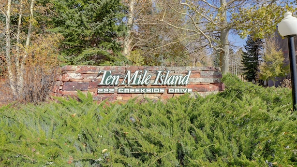 En skylt för Ten Mile Island, placerad på adressen 222 Creekside Drive, omgiven av träd och grönska.