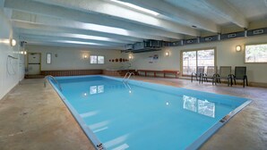 En inomhuspool med klart vatten, en stege och en bänk placerad nära poolen.