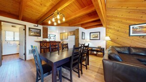 Un intérieur de chalet chaleureux avec un coin repas, une cuisine et un canapé en cuir.