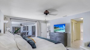 Una camera d'albergo moderna con un ampio letto, una TV a schermo piatto e una ventola a soffitto.