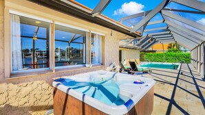 Un'area idromassaggio con vista su una piscina e un portico coperto.