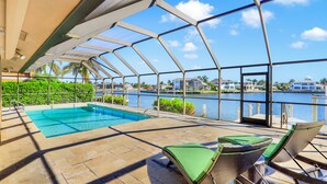 Una piscina scoperta coperta con lettini e vista su un corpo d'acqua e edifici.