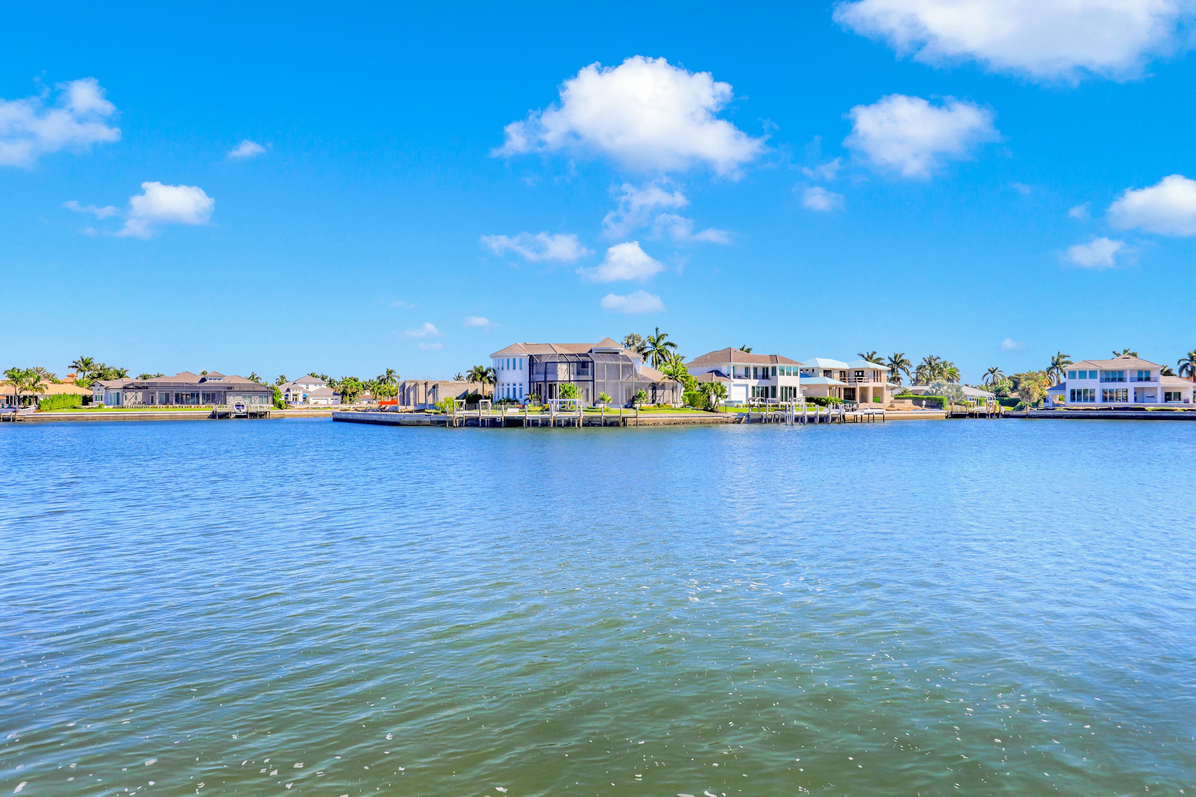 A waterfront property with multiple houses, a dock, and a clear blue sky.