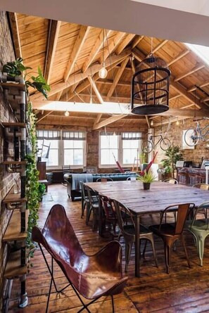 A rustic dining area with a wooden table and chairs, surrounded by brick walls and wooden beams. - East London loft penthouse with epic roof terrace and loads of space (London)