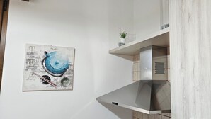 A modern kitchen with a stainless steel range hood, a wall-mounted shelf with a potted plant, and a piece of abstract art. - Villa RELAX SALENTO GALLIPOLI terrace sea view wifi (Torre Suda)