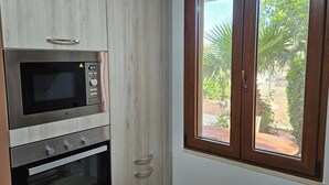 Une cuisine équipée d’un four à micro-ondes et d’un four encastrés, et dotée d’une fenêtre donnant sur un espace verdoyant.