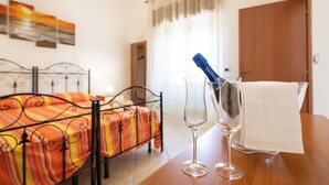 Une chambre d’hôtel avec un lit, une table sur laquelle se trouve une bouteille de champagne, deux verres et une serviette blanche.