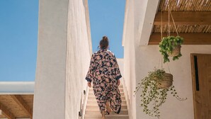 Eine Person geht eine Treppe in einem modernen Gebäude hinunter, über ihr erstreckt sich ein klarer Himmel.