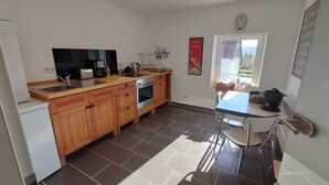 Une cuisine moderne avec des meubles en bois, un four encastré, un évier et une fenêtre donnant sur l’extérieur.
