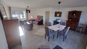 Un salon spacieux comprenant un coin repas, une cheminée et une grande fenêtre.
