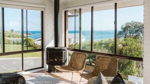 A room with large windows, a fireplace, wicker chairs, and a view of the sea. - The G At Gerroa (Gerroa)