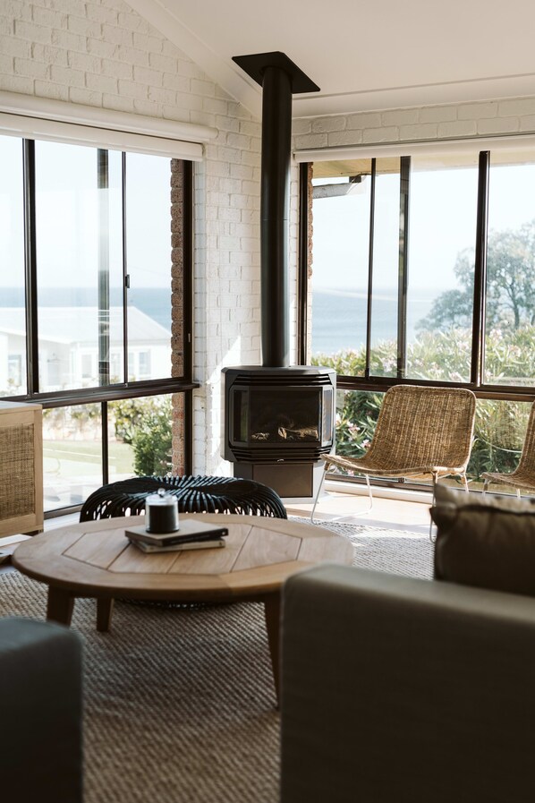 A cozy living room with a fireplace, large windows, and comfortable seating.