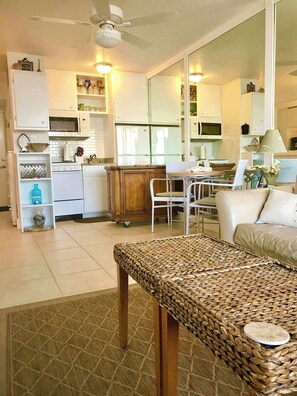 Un espacio habitable compacto con kitchenette, comedor y zona de estar con una mesa de fibras naturales.
