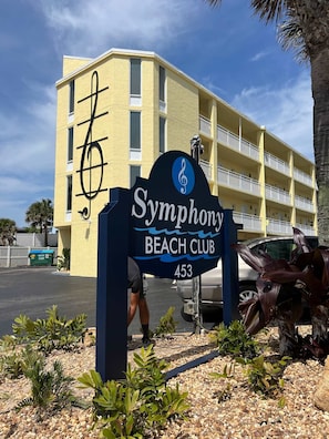 Señal del Symphony Beach Club, con un edificio al fondo.