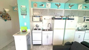 Een knus woongedeelte met een kitchenette, een bank en een eettafeltje.