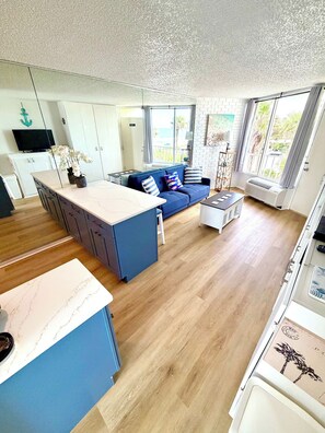 A modern living space with a kitchen, dining area, and a large window providing a view of the outdoors.