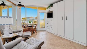 A room with a sofa, a dining table with chairs, a TV, and a wardrobe.