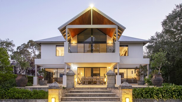 A modern two-story house with a prominent balcony, a well-lit entrance, and a stone staircase leading up to the front door. - LUXURIOUS & INVITING TWO STOREY HOME WITH COMFORTABLY CASUAL COASTAL VIBE (Marybrook)