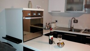 A modern kitchen with a built-in oven, a sink, and a countertop with a wine bottle and glass. - HEART OF FLORENCE APARTMENT (Firenze)