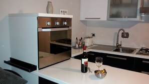 Eine moderne Küche mit Backofen, Spüle und einer Arbeitsplatte, auf der sich eine Weinflasche und ein Glas befinden.