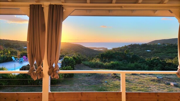 Un balcón con vista a una puesta de sol sobre un paisaje montañoso.