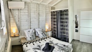 Un dormitorio con cama, lámparas de noche, una ventana con cortinas y un equipo de aire acondicionado.