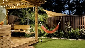 A wooden deck with string lights, a hammock, and a patio area with a table and chairs. - Tropical Private Beach Studio Apt #1 @ Jobos Beach (Jobos, Isabela, Puerto Rico)