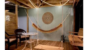A cozy room with a hammock swing, a round woven wall decoration, and a small round table with chairs. - Tropical Private Beach Studio Apt #1 @ Jobos Beach (Jobos, Isabela, Puerto Rico)